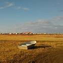 Abandoned boat is far from town on tundra vegetation.